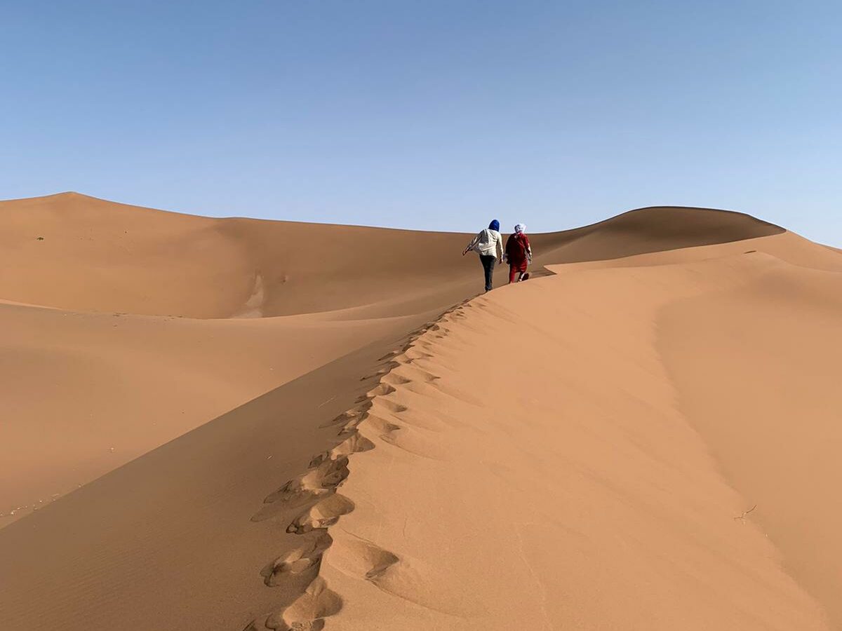 1 Nomade et un marcheur marchent sur la crête d'une dune