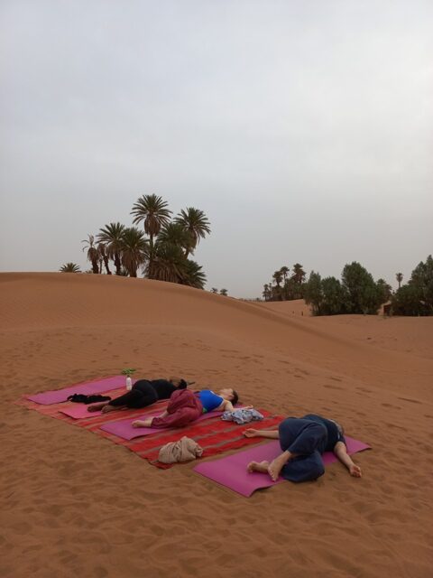 Femmes faisant du yoga dans les dunes